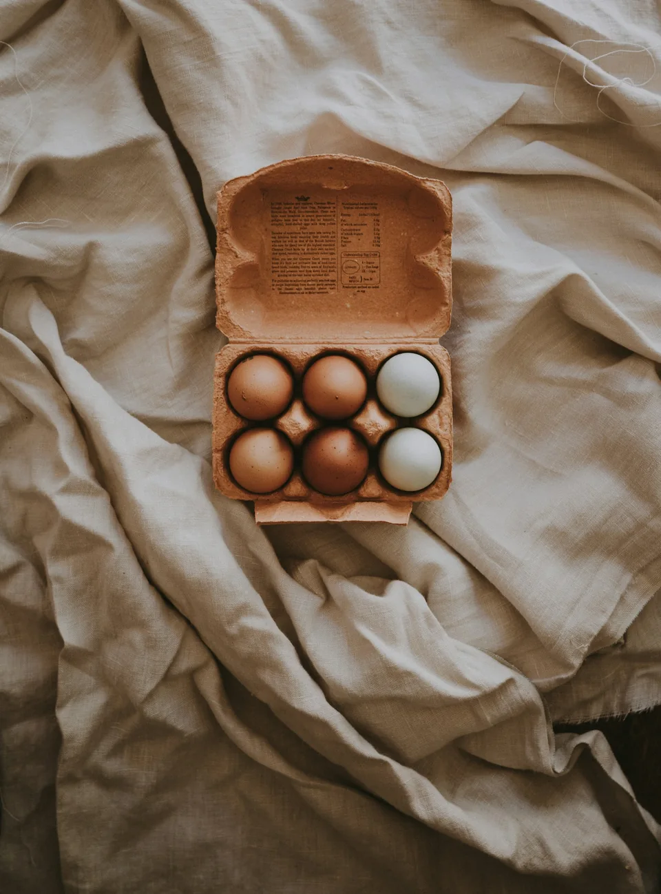 Six œufs dans une boîte en carton, photographiés à la lumière naturelle